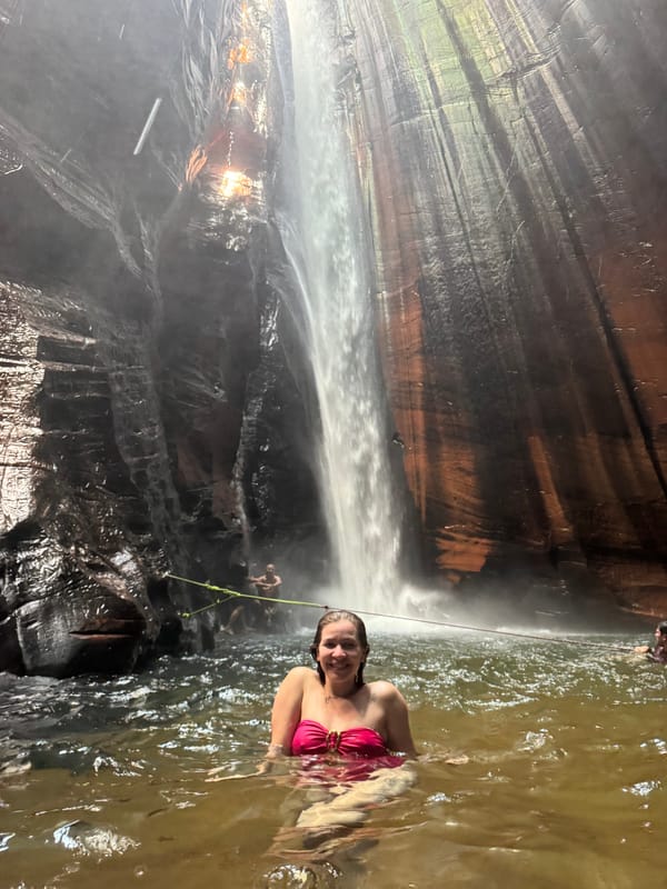 Mulher na água ao pé da queda alta e fina do Santuário, entre paredões de arenito listrado