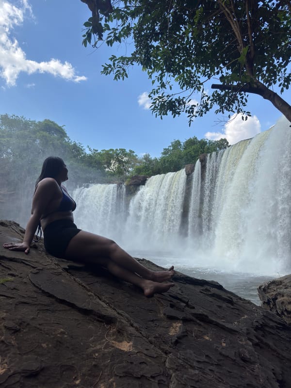 Mulher recostada numa pedra diante da cachoeira larga do São Romão