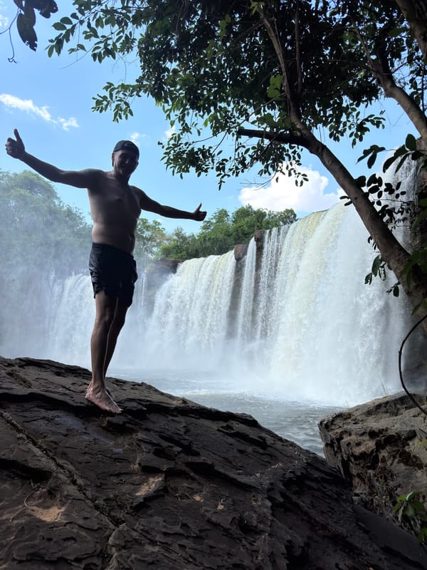 Homem de braços abertos numa pedra diante da cachoeira larga do São Romão