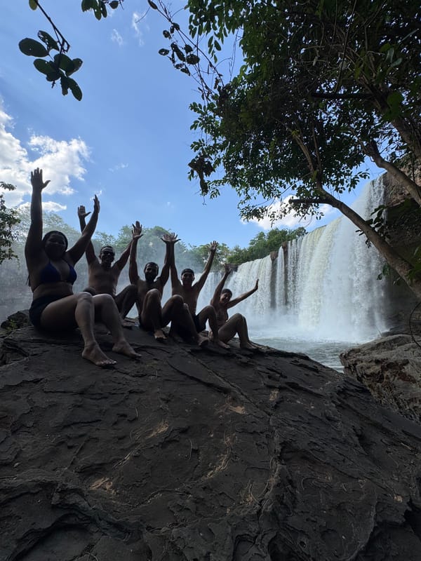 Grupo de braços para cima numa pedra ao lado da cachoeira larga do São Romão