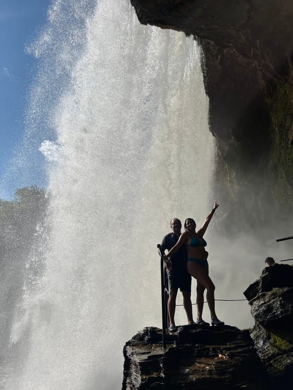 Casal numa pedra ao lado da cortina d’água do São Romão, contra o sol