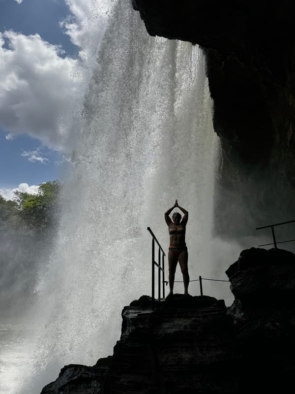 Silhueta de uma pessoa de braços erguidos atrás da cortina d’água do São Romão