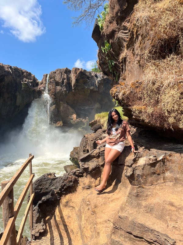 Mulher sentada nas pedras ao lado da Cachoeira do Prata, sob céu azul
