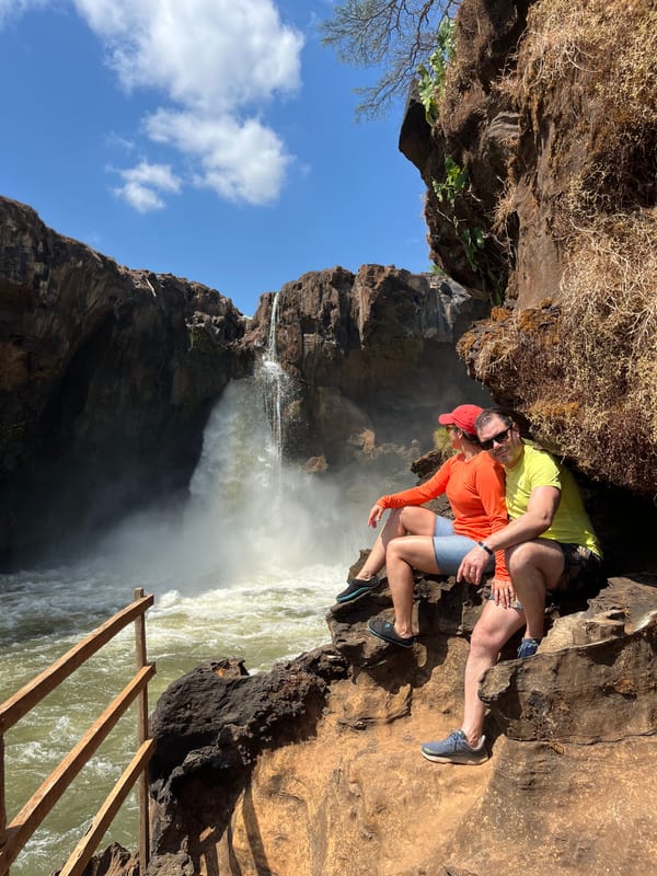 Casal sentado nas pedras diante da Cachoeira do Prata