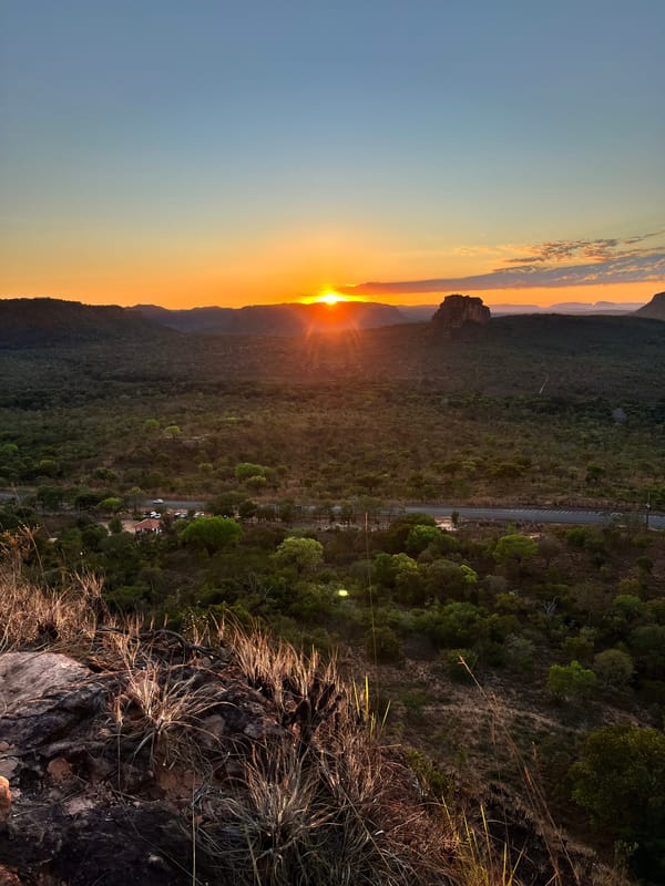 Sol se pondo atrás das mesas, visto do alto do Portal da Chapada, com o cerrado e a rodovia lá embaixo
