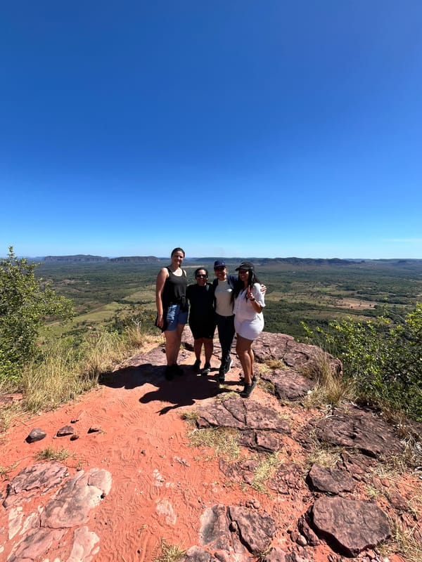 Grupo pequeno no alto do Morro do Chapéu, visto de longe, sobre a terra vermelha e a planície