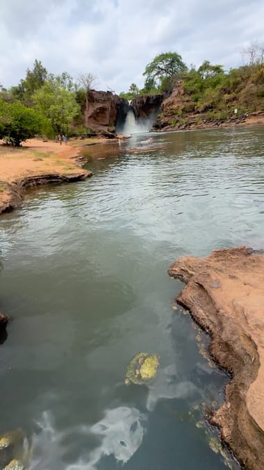 O rio correndo entre pedras, com a queda do Prata ao fundo